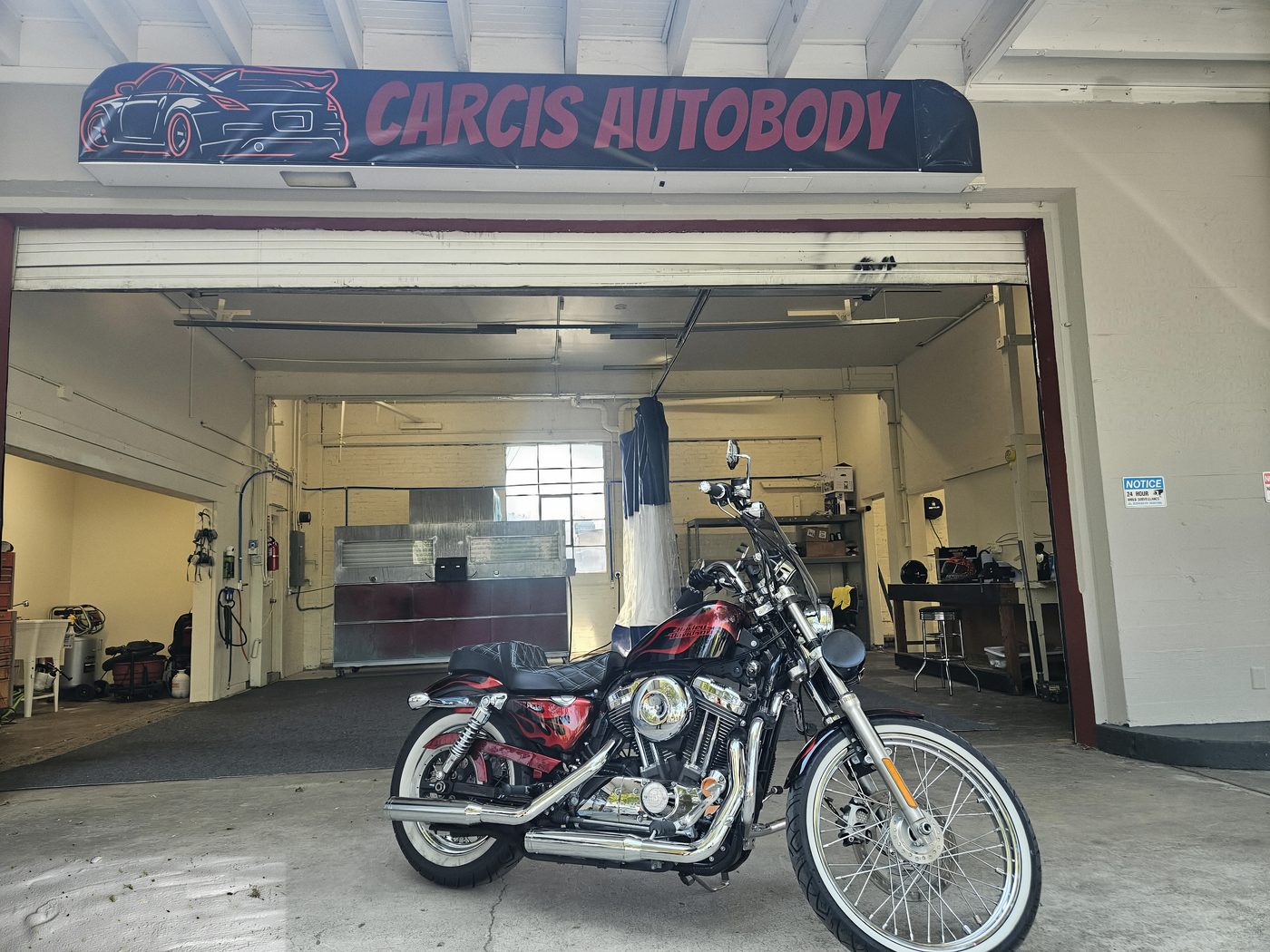 Custom motorcycle parked outside the Carcis Autobody Repair shop