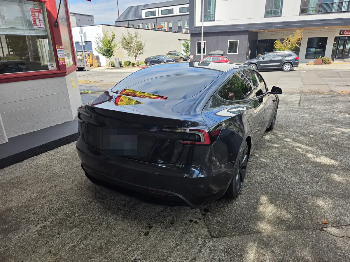 The repaired 2024 Tesla Model 3 in metallic gray, parked outside the shop.